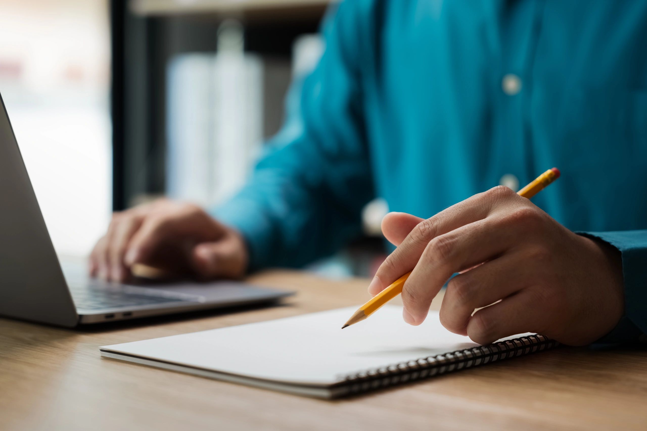 Hand writing in a notebook with a pencil