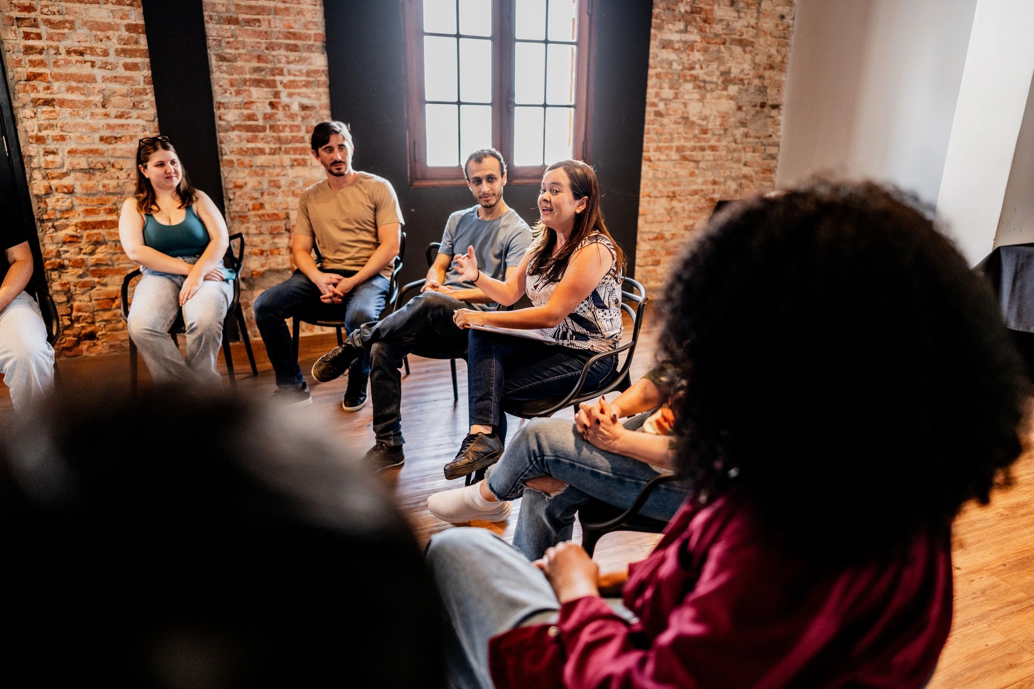 Facilitator speaking with a therapy group, representing community support resources